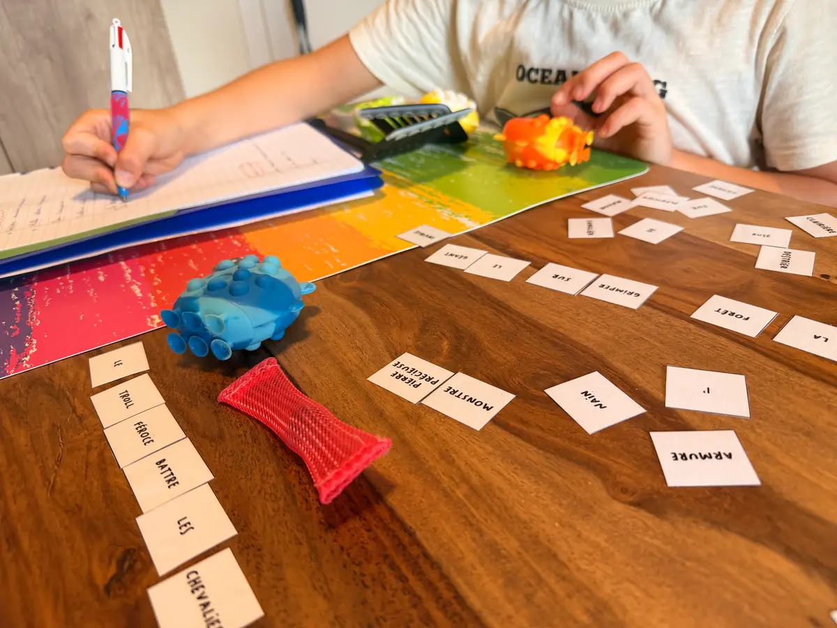 les mains d'un enfant qui joue à un jeu de grammaire et ecrit sa phrase